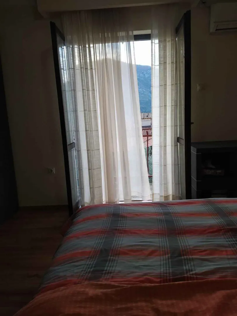 Spavaća soba sa izlazom na balkon kroz otvorena vrata.