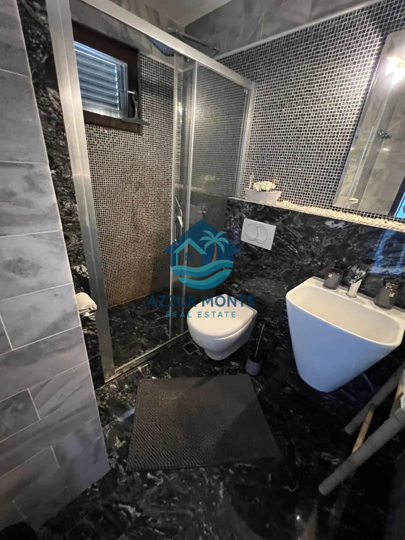 Modern bathroom with a walk-in shower, toilet, and washbasin.