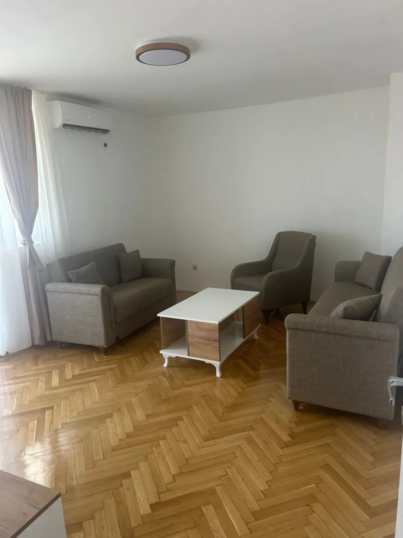 Dnevna soba sa garniturom za sjedenje, stočićem i drvenim podom.