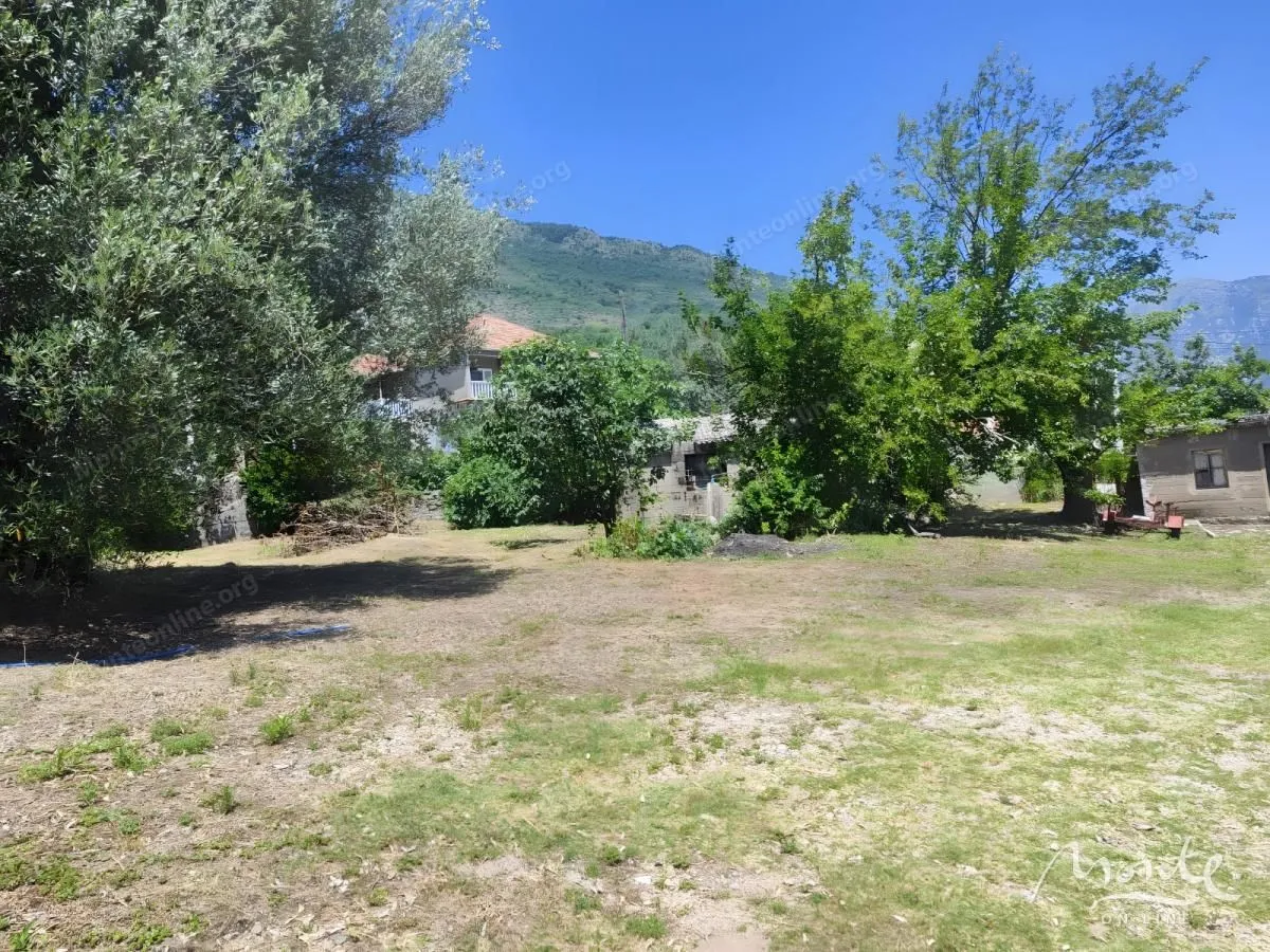 Prostrano dvorište sa zelenilom i pogledom na okolne planine.