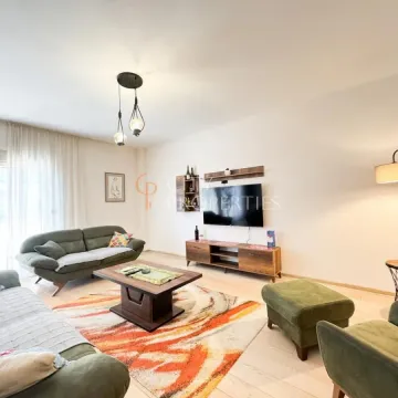 Dnevni boravak opremljen garniturom, stočićem i televizorom na zidu. - image 13