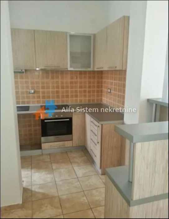 Smaller kitchen with wooden cabinets and tiled walls.
