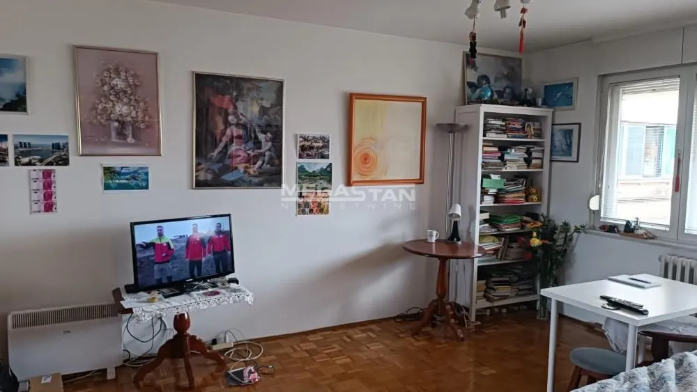 Dnevna soba sa nameštajem, televizorom i slikama na zidu.