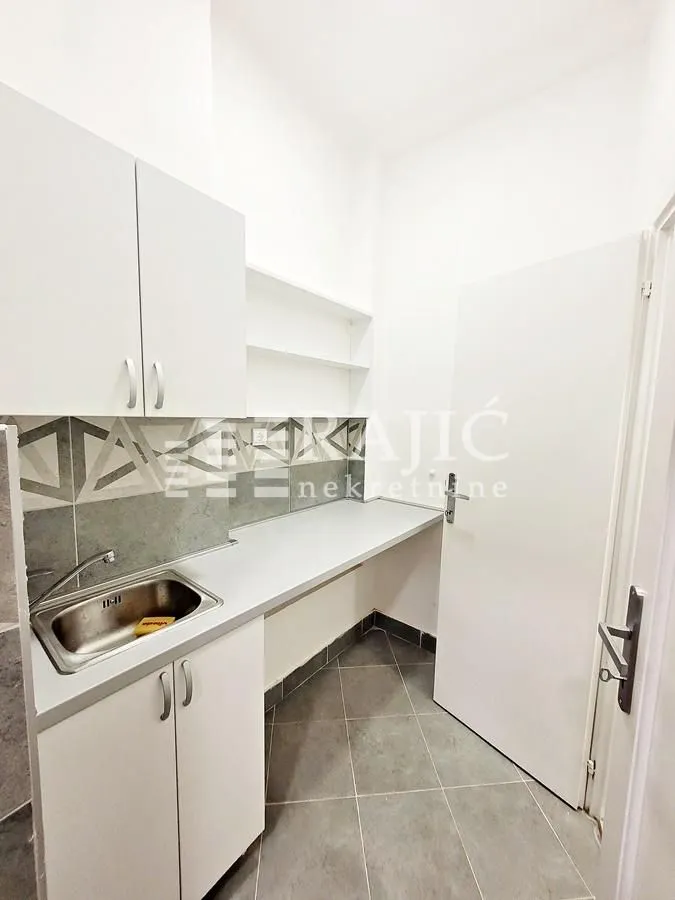 Smaller white kitchen with a sink and countertops.