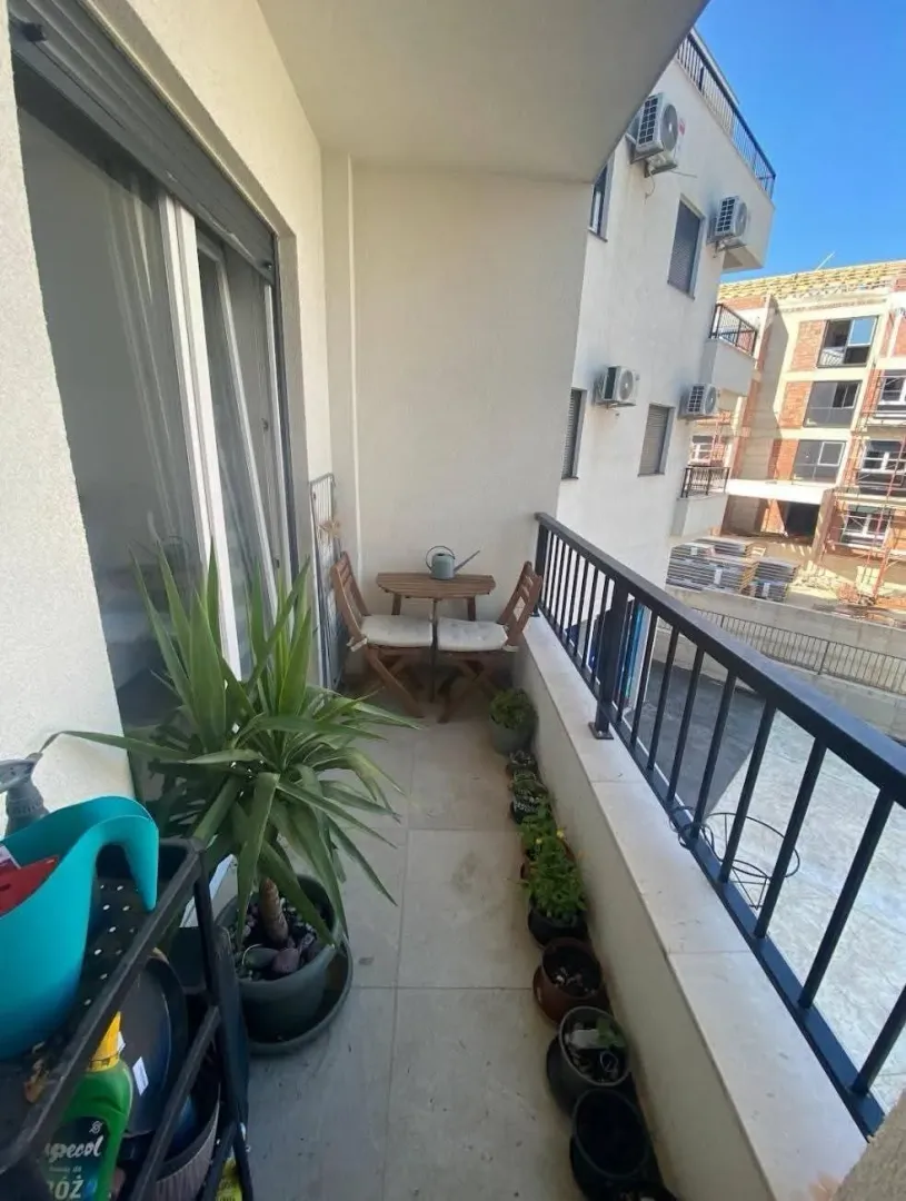 Namtješten balkon sa stolom, stolicama i saksijama sa cvijećem.