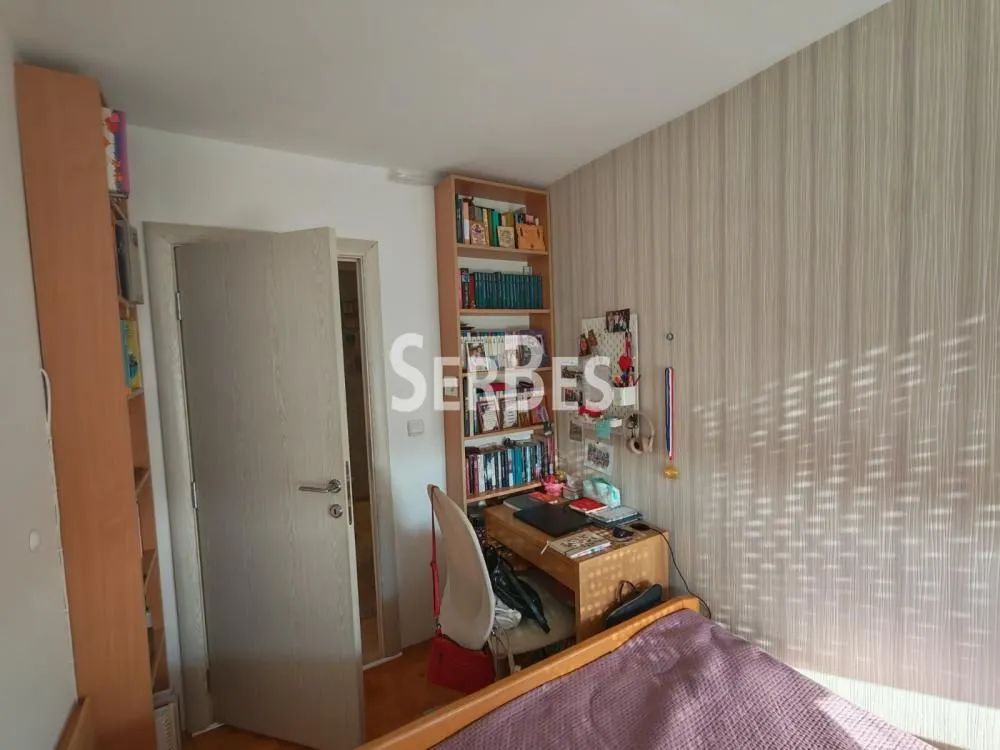 Dečja soba sa krevetom, radnim stolom i policama za knjige.