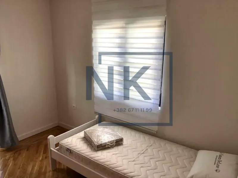 Smaller bedroom with a bed and a window with blinds.