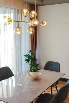 Dining area with a table, chairs, and a modern chandelier. - image 6