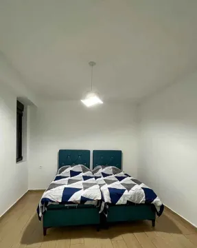 Spavaća soba sa dva spojena kreveta i bijelim zidovima. - image 4