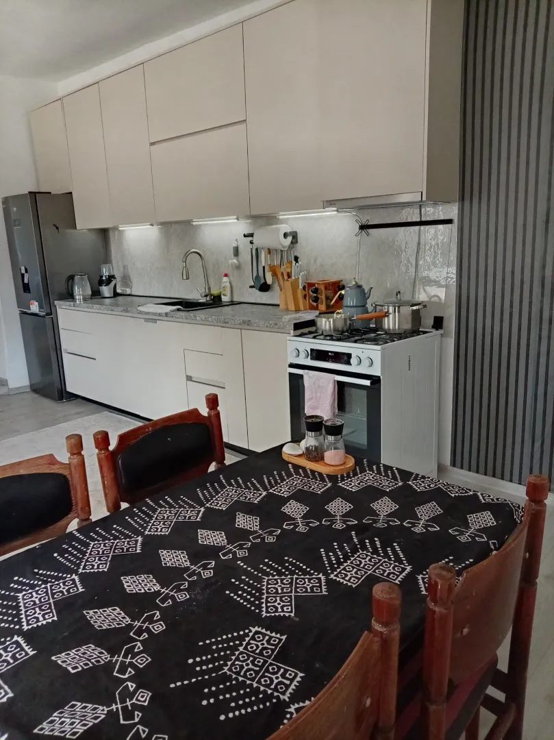 Moderna kuhinja sa trpezarijskim stolom i ugradnim elementima.