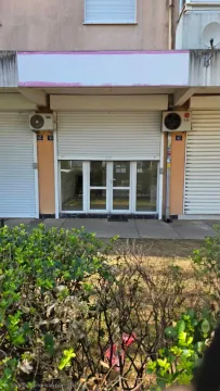 Exterior view of the commercial space with a lowered rolling shutter and glass entrance. - image 4