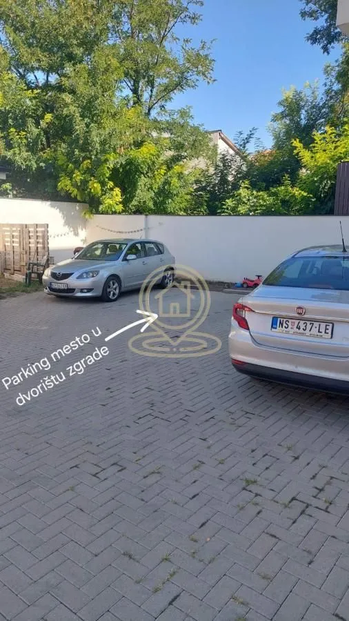 Parking mesto u dvorištu zgrade sa popločanom površinom.
