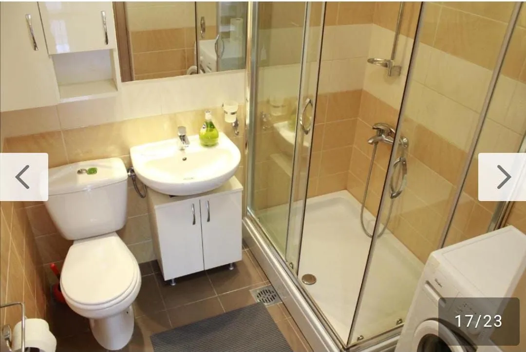 Small bathroom with a shower cabin, washbasin, and washing machine.
