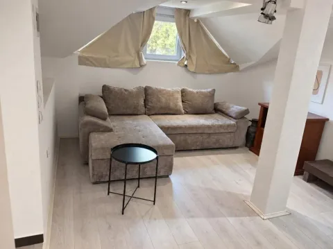 Attic living room with a sectional sofa and a small coffee table. - image 3