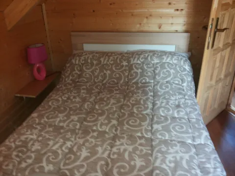 Spavaća soba obložena drvetom sa bračnim krevetom. - image 12