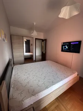 Bright bedroom with a double bed, built-in wardrobe, and wall-mounted TV. - image 8