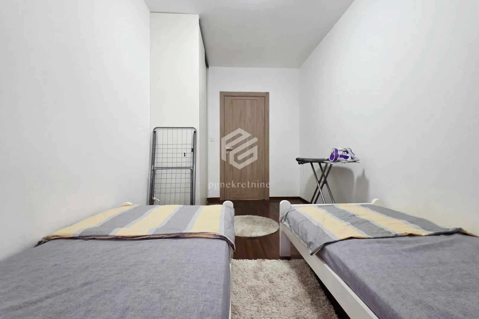 Bedroom with two single beds and white walls.