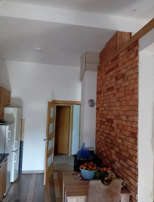 Manja kuhinja sa trpezarijskim stolom i zidom obloženim ciglom.