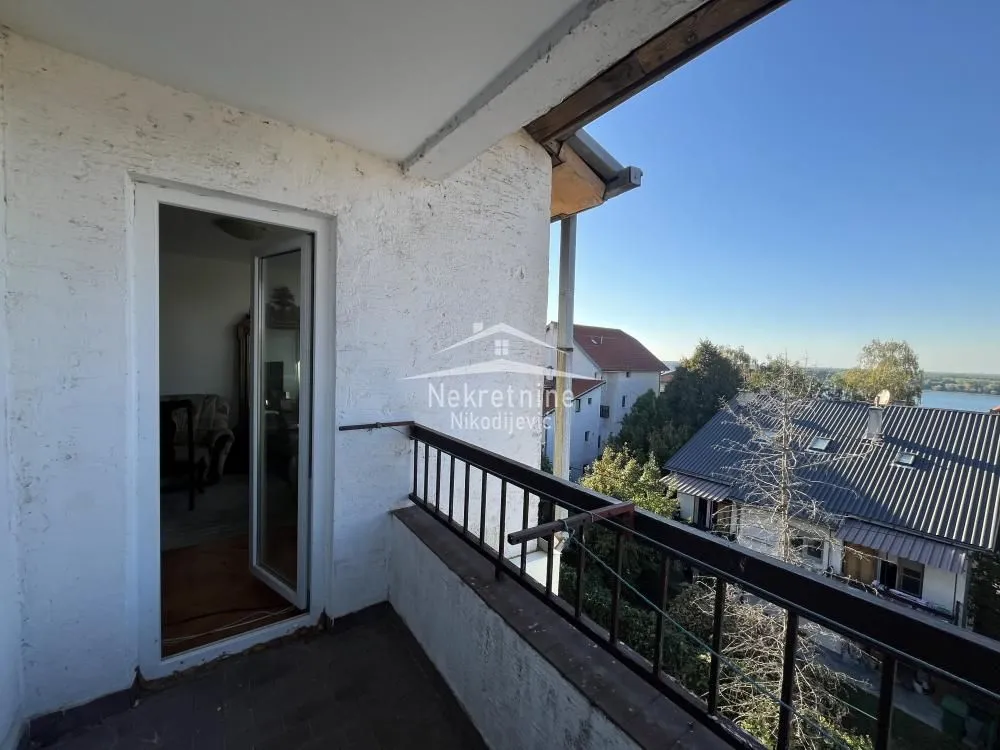 Manji natkriveni balkon sa metalnom ogradom i pogledom na okolinu.