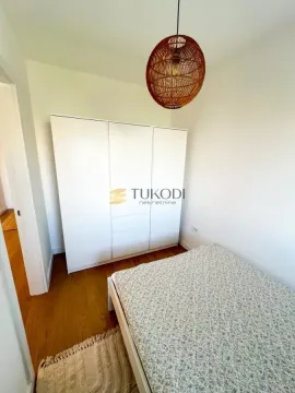 Small bedroom with a bed, a white wardrobe, and a woven pendant light. - image 6