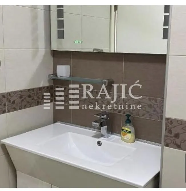 View of the bathroom with a sink, mirror, and tiles.