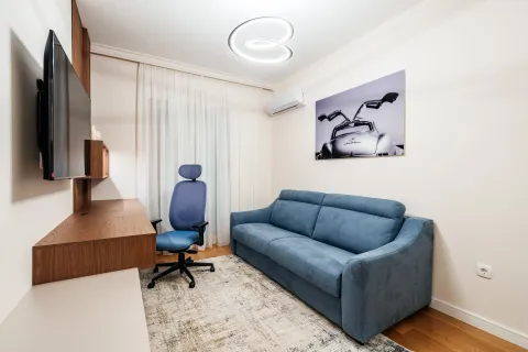 Living room with a blue sofa, desk, and TV. - image 5