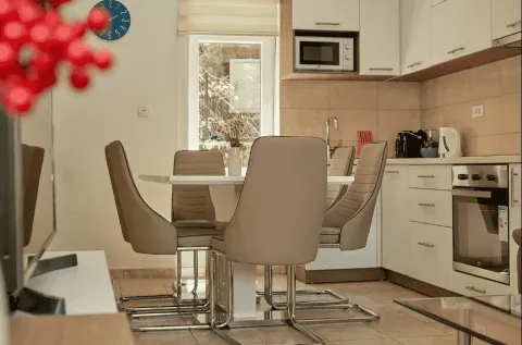 Kuhinja sa trpezarijom opremljena bijelim elementima i modernim stolom sa stolicama. - image 16
