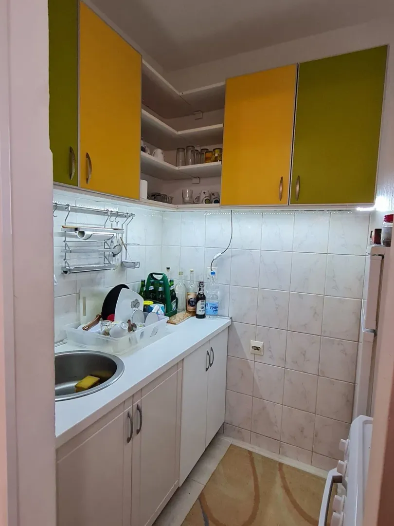 Small kitchen with yellow and green cabinets and a sink.