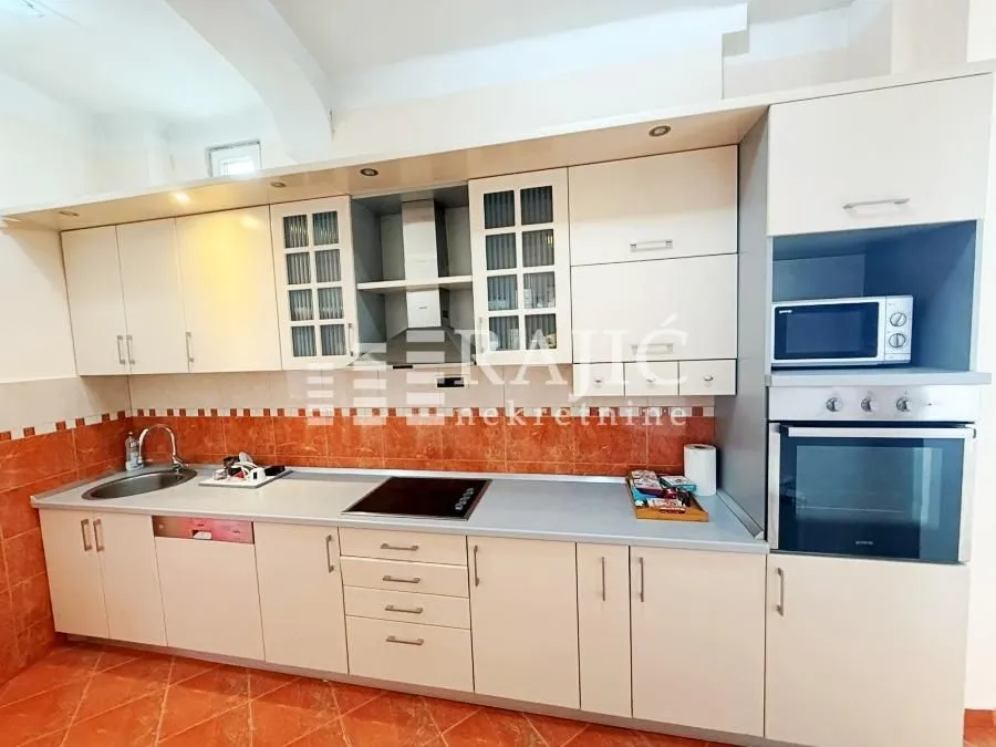 Equipped kitchen with white cabinets and built-in appliances.