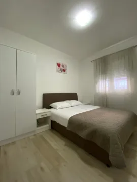 Uređena spavaća soba sa bračnim krevetom, garderoberom i prozorom. - image 4