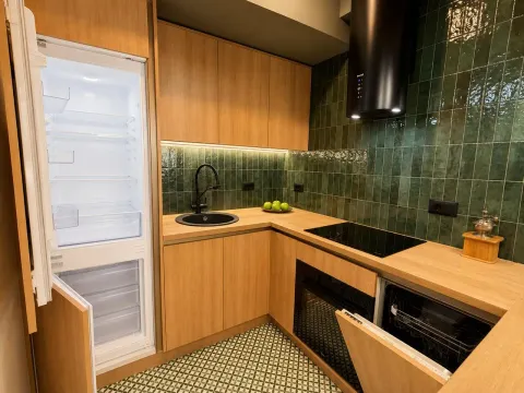 Modern kitchen with wooden elements, green tiles, and built-in appliances. - image 2