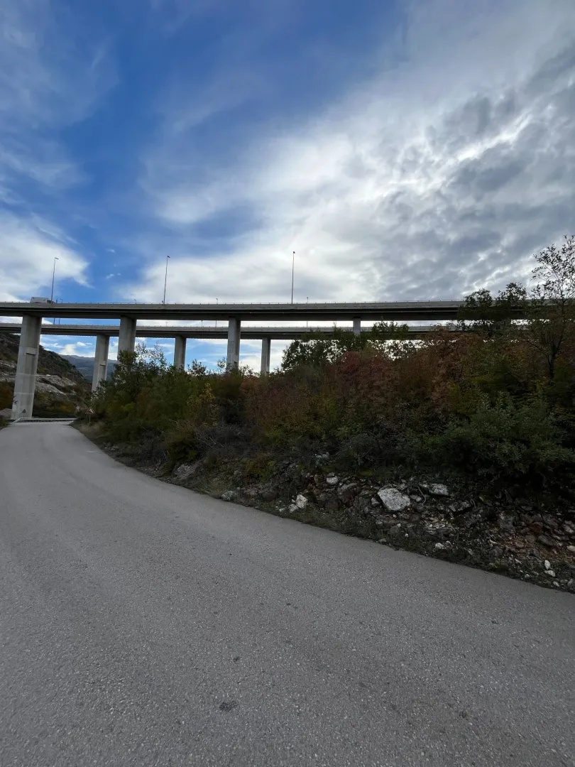 Asfaltni put koji vodi prema velikom betonskom vijaduktu u prirodi.