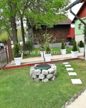 Uređeno dvorište sa stazom, ukrasnim rastinjem i drvenom kućom u pozadini. - image 3