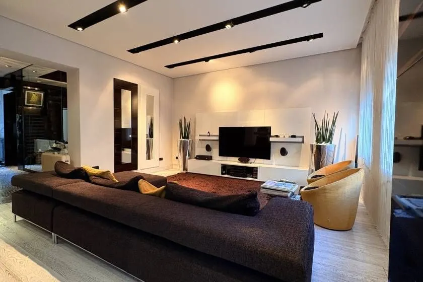 Modern living room with a large sectional sofa, television, and modern lighting.