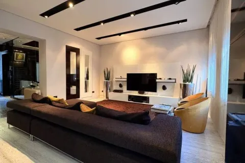 Modern living room with a large sectional sofa, television, and modern lighting. - image 3