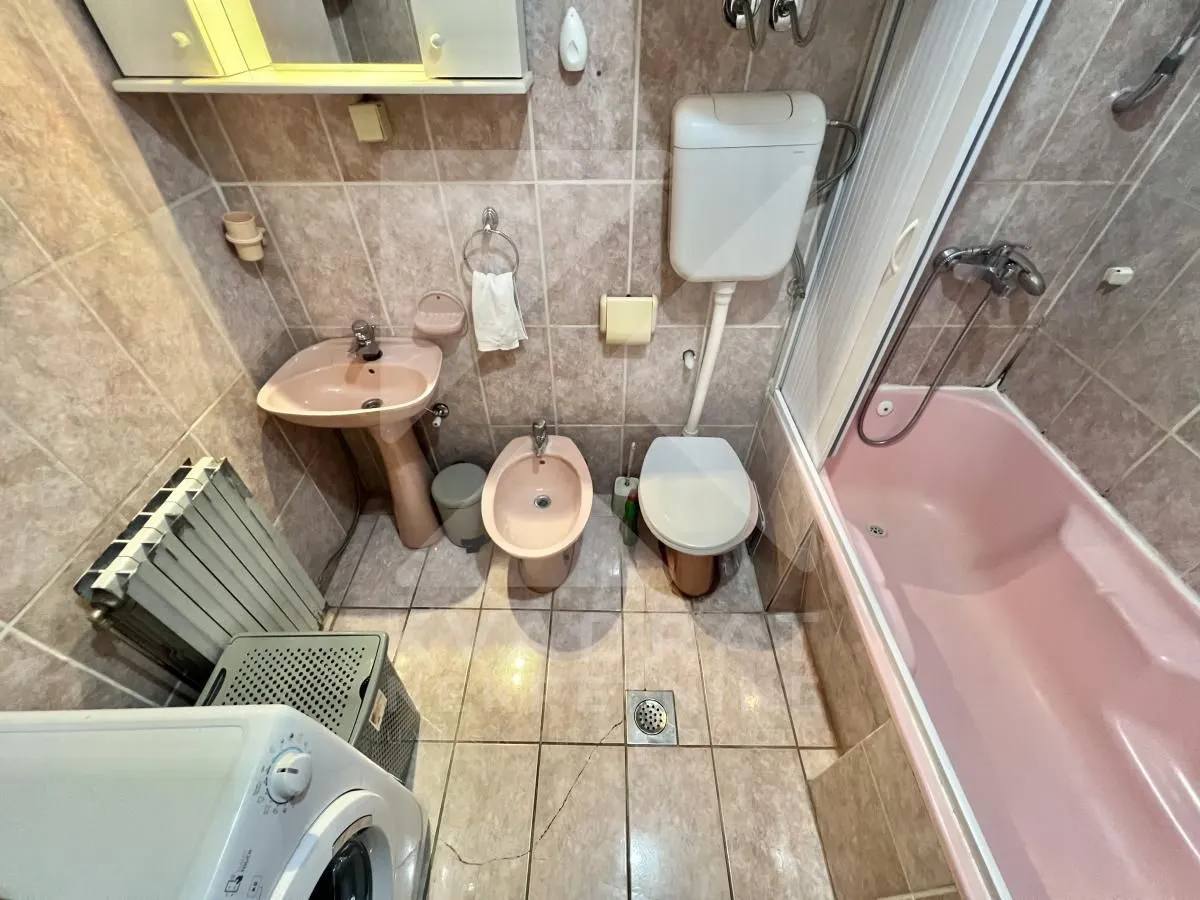 Bathroom equipped with a sink, bidet, toilet, and pink bathtub.