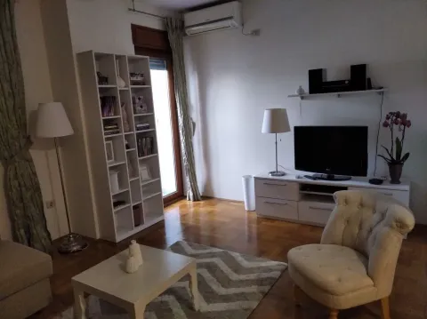 Svijetla dnevna soba sa foteljom, policom za knjige i televizorom. - image 7