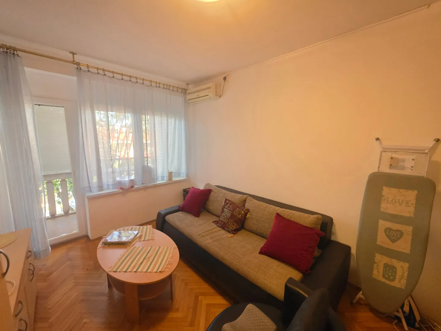Dnevna soba sa garniturom, stočićem i izlazom na terasu.