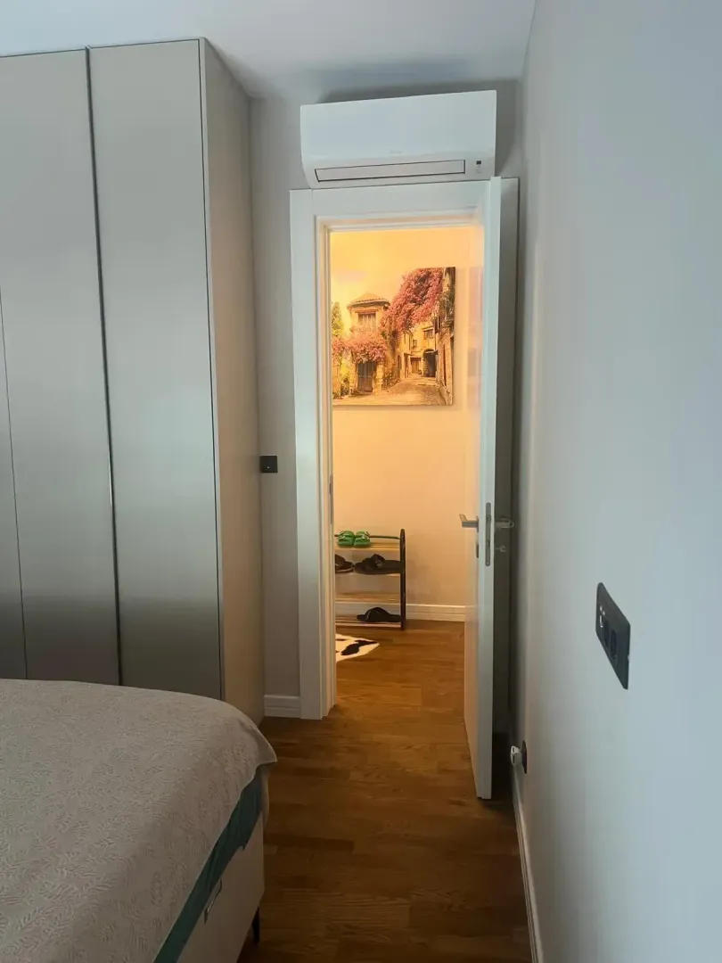 Pogled iz spavaće sobe prema hodniku sa otvorenim vratima.