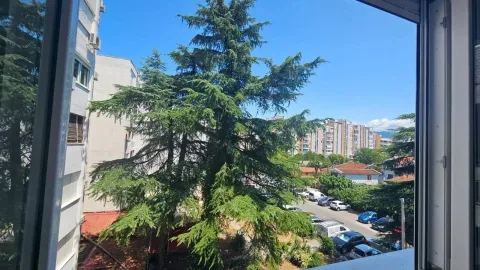 Pogled sa prozora na okolne zgrade i zeleno drveće. - image 8