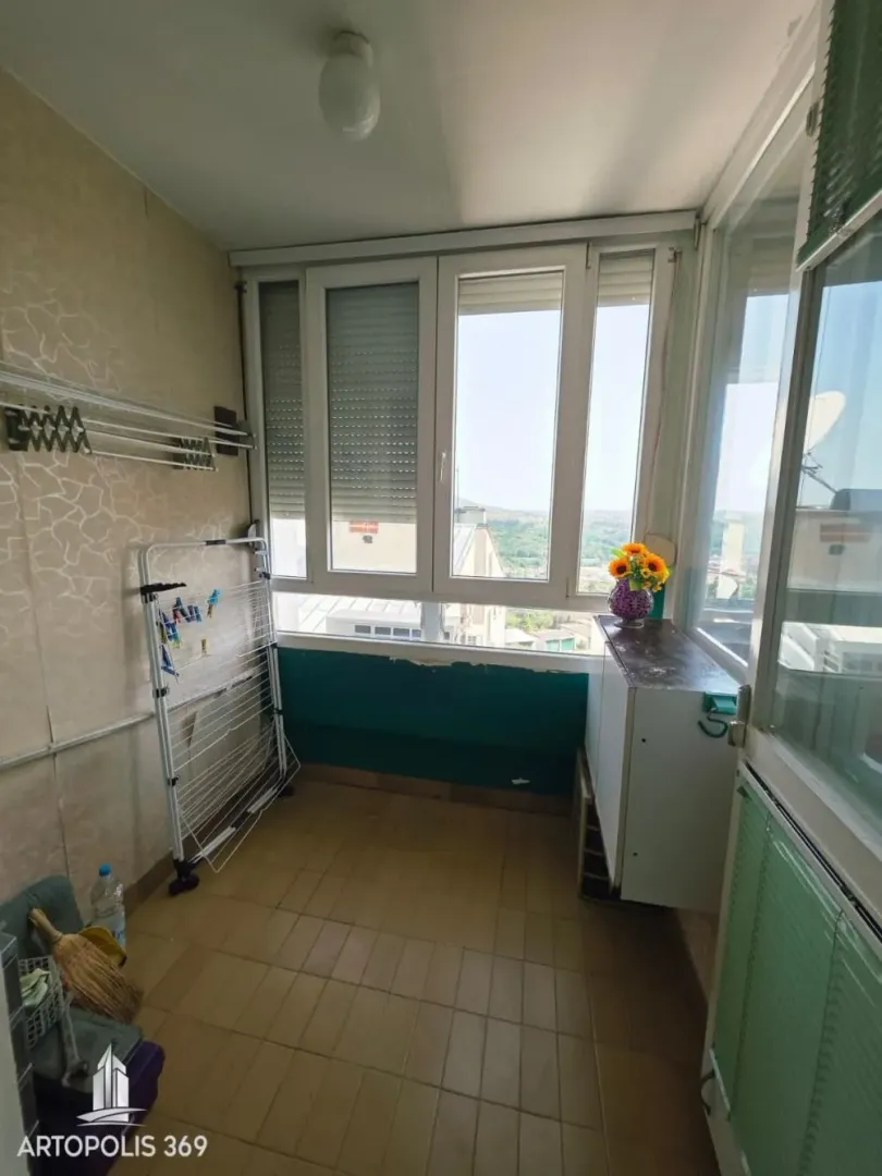 Zastakljeni balkon sa keramičkim pločicama na podu i sušačem za veš.