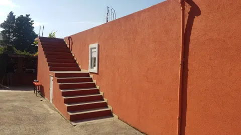 Spoljašnji dio objekta sa stepeništem i fasadom narandžaste boje. - image 7