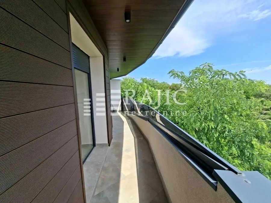 Spacious balcony with wooden cladding and a view of greenery.