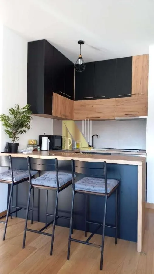 Small kitchen with a breakfast bar and black and wooden cabinets.