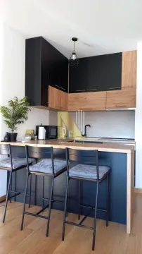 Small kitchen with a breakfast bar and black and wooden cabinets. - image 3