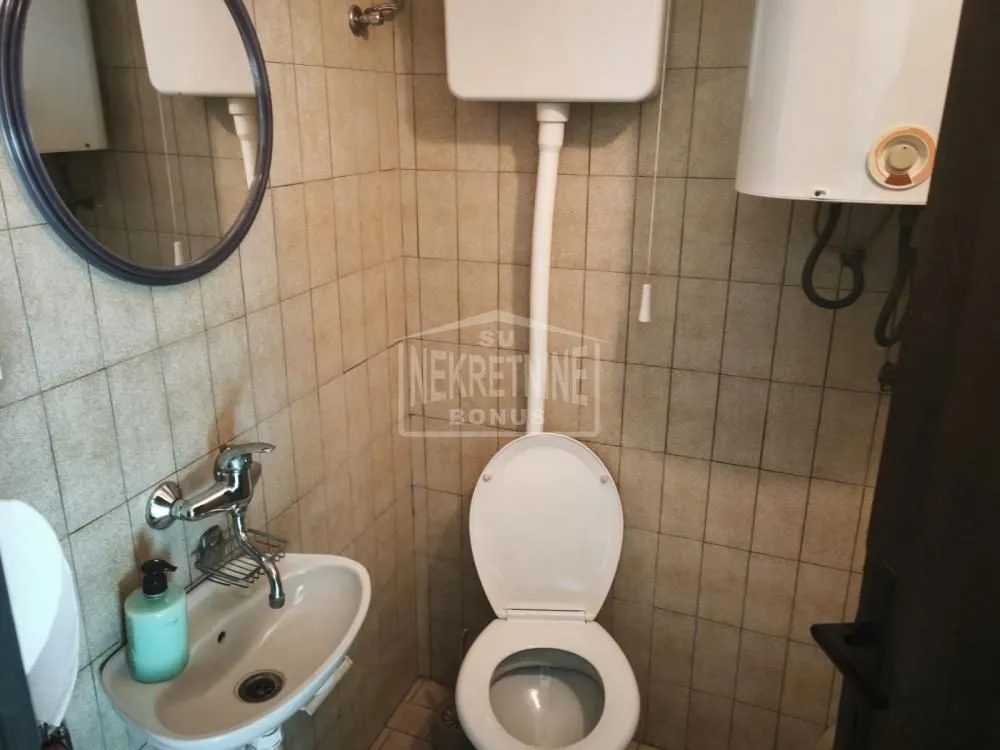 Small bathroom with a sink, toilet, and wall-mounted water heater.
