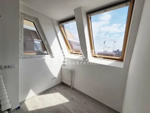 Empty attic room with slanted windows and laminate flooring. - image 5