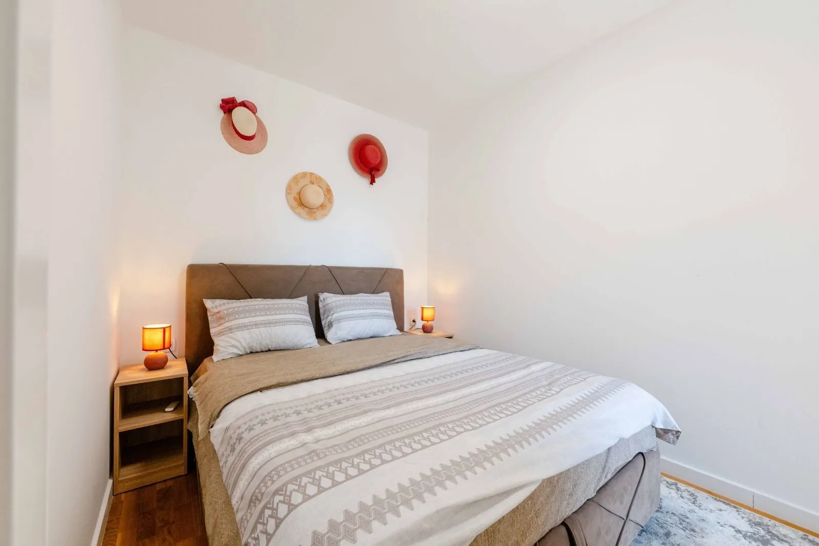 Furnished bedroom with a double bed, nightstands, and wall decoration.