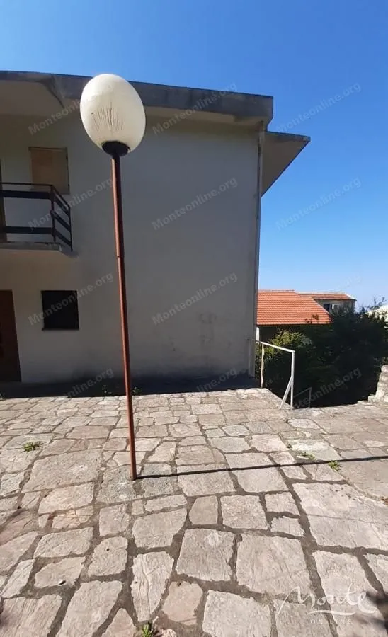 Paved courtyard in front of the house with a street lamp.