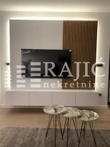 Dnevna soba sa modernim TV elementom i stočićima.